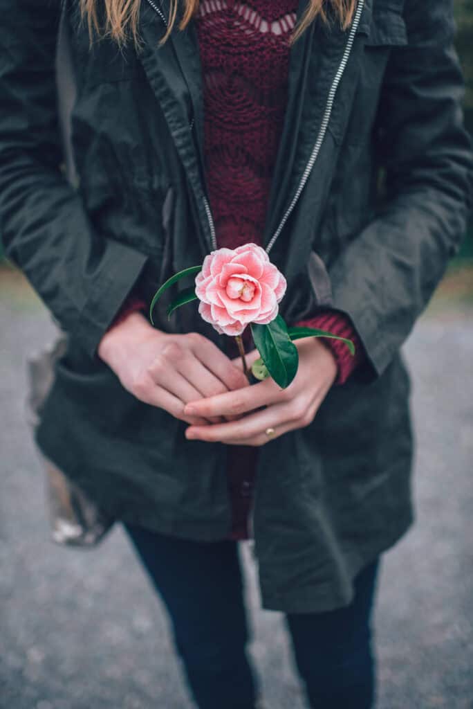 Ricardo Ferreira Switches Soccer Allegiance to Canada Person holding a pink flower with green leaves outdoors.